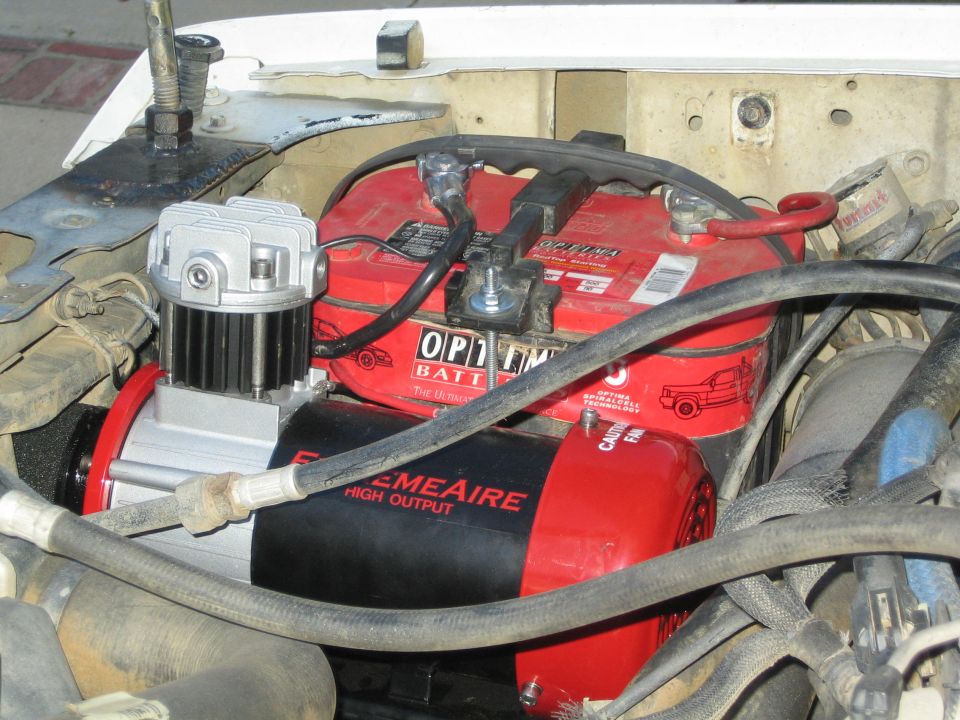 Engine bay with red Optima batteries and a black ExtremeAire High Output air compressor