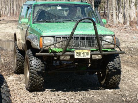 1994 Ford Bronco - This modified green Jeep Cherokee features a snorkel and a prominent bull bar, seen from the front.