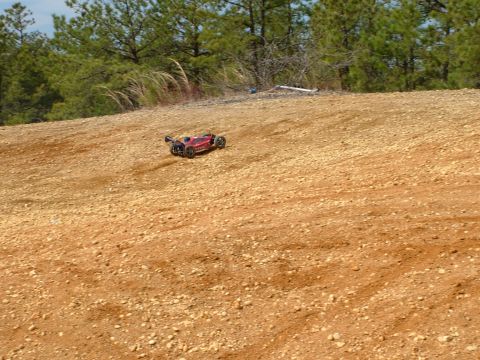 1994 Ford Bronco - A red remote control car navigates a rocky, dirt terrain under a clear sky.
