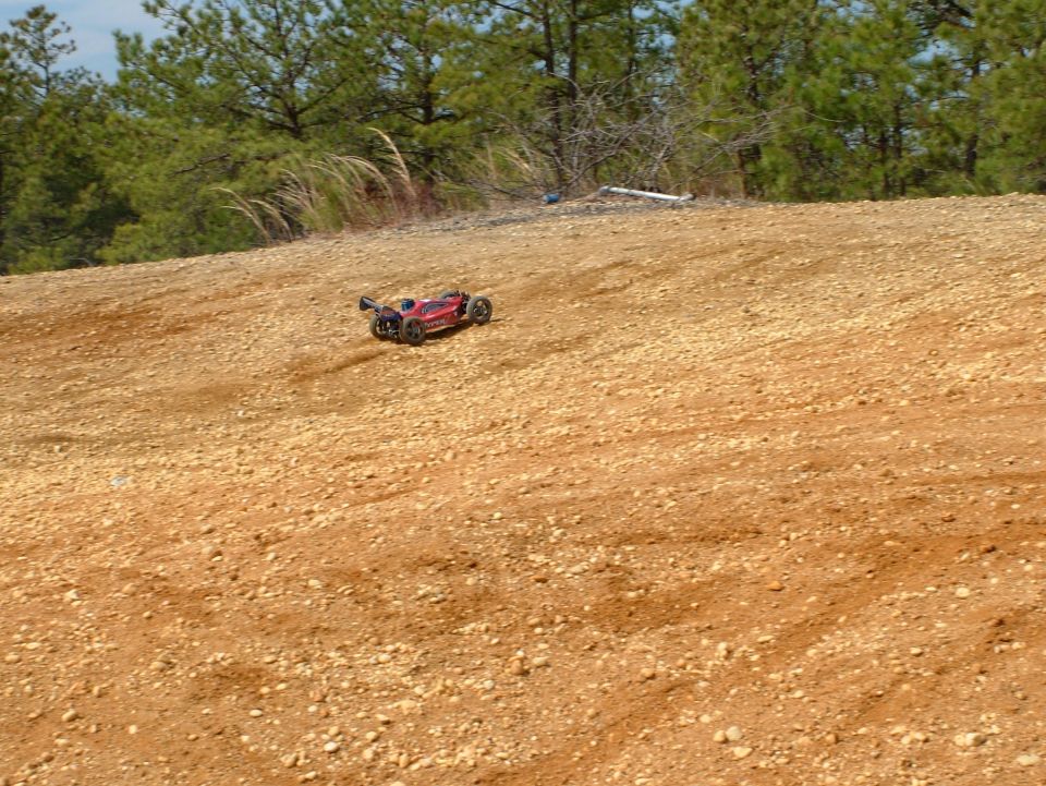 Red remote control car driving on a dirt hill