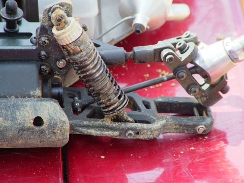 1994 Ford Bronco - This image shows a close-up view of the suspension system of a remote control car, covered in dirt and debris.