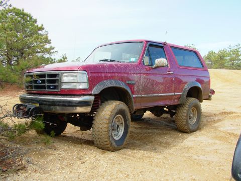 1994 Ford Bronco - This red 1994 Ford Bronco is equipped with off-road tires and a front-mounted winch, suggesting it is prepared for terrain.