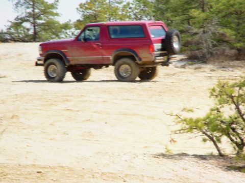 1994 Ford Bronco - This red 1994 Ford Bronco is shown off-road with a spare tire mounted on the rear.