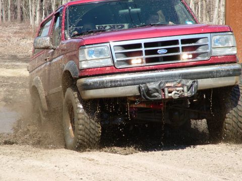 1994 Ford Bronco - This red Ford Bronco is kicking up mud as it navigates an off-road trail.