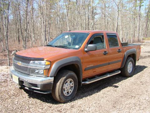 1994 Ford Bronco - This orange Chevrolet Colorado pickup truck is seen from a 3q-front angle in a wooded area.