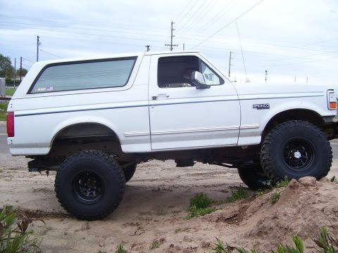 1994 Ford Bronco - This lifted 1994 Ford Bronco is shown from the side, parked on uneven terrain.