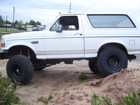 1994 Ford Bronco - A white 1994 Ford Bronco is shown with a lifted suspension and off-road tires.