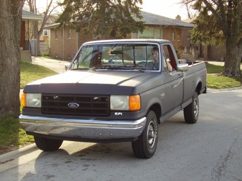 1996 Ford F-150 - This gray Ford F-150 pickup truck is parked on a street in front of a house.