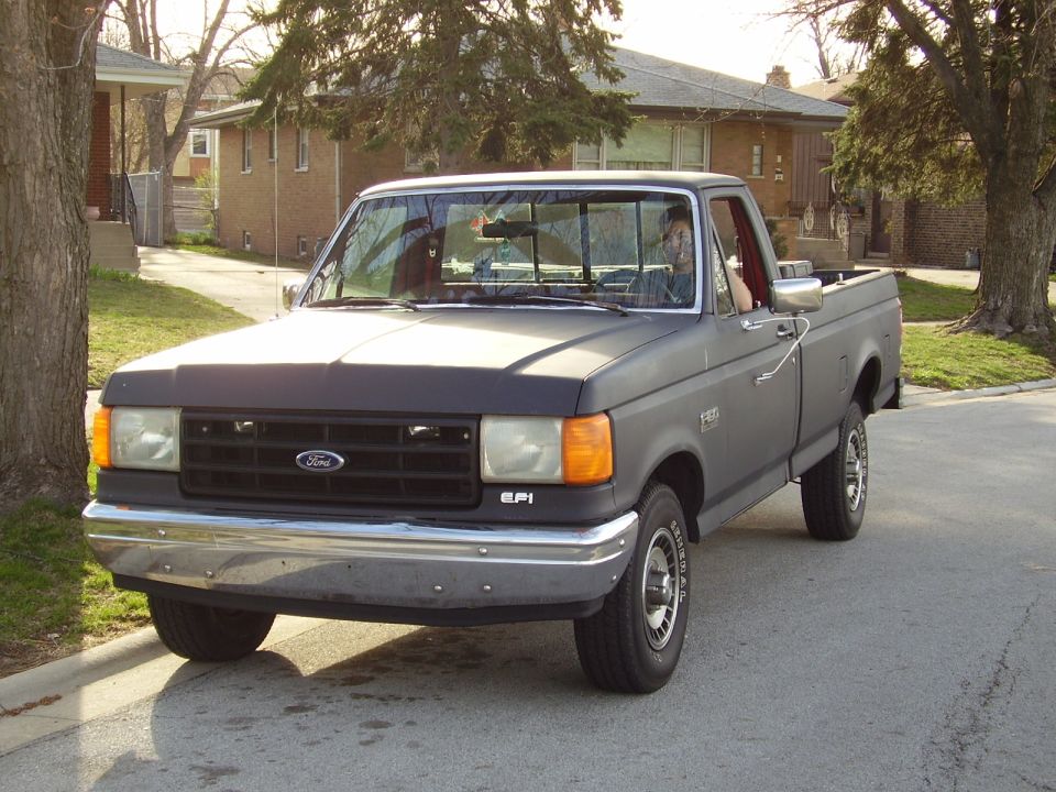 Gray Ford F-150 pickup truck parked on a residential street, front 3/4 view