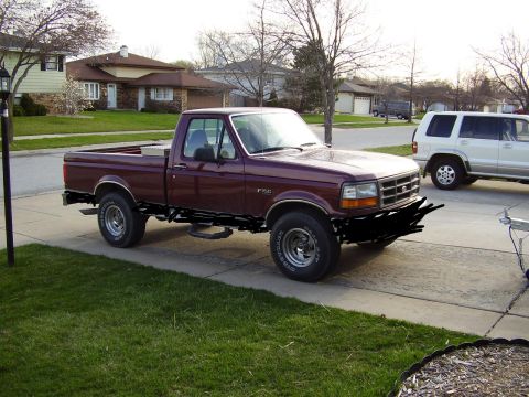 1996 Ford F-150 - This maroon Ford F-150 pickup truck is parked in a suburban driveway next to a white SUV.