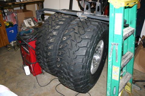 1995 Ford Bronco - Two large off-road tires are shown mounted on rims, with a green ladder and red equipment nearby.