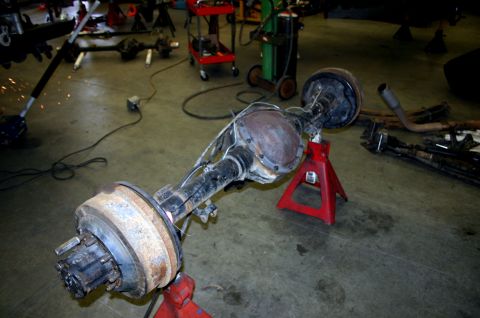 1995 Ford Bronco - A rear axle assembly is supported by red jack stands in a workshop environment.