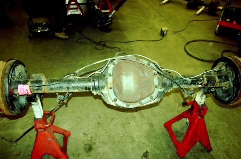 1995 Ford Bronco - Rear axle assembly, likely from a truck or SUV, is supported by red jack stands in a workshop setting.