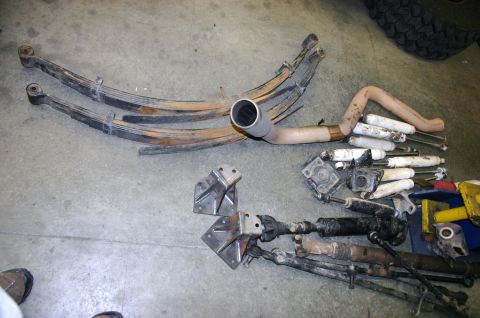 1995 Ford Bronco - Collection of vehicle suspension and exhaust components on a workshop floor.