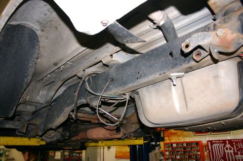 1995 Ford Bronco - The undercarriage of a vehicle is shown, including the fuel tank and exhaust components, while elevated on a lift.