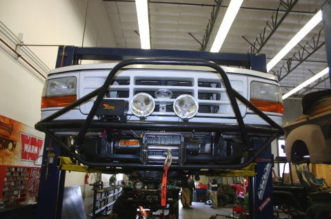 1995 Ford Bronco - A white 1995 Ford Bronco is lifted on a service rack, its front end with a custom brush guard and winch.