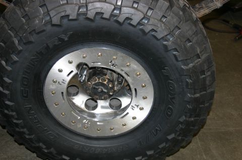 1995 Ford Bronco - Close-up of a large off-road tire and custom wheel, showing the intricate details of the hub and lug nuts.