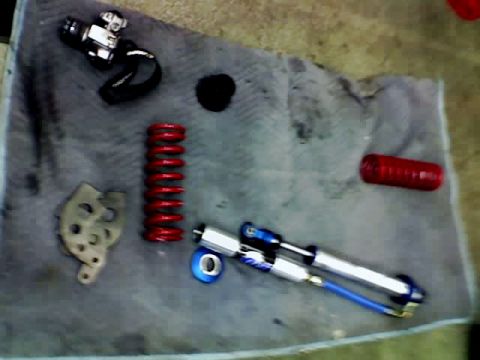 1995 Ford Bronco - Various automotive suspension parts, including a coilover shock and spring, are laid out on a cloth.