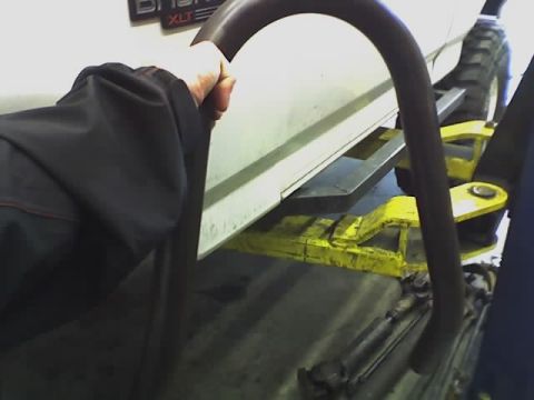 1995 Ford Bronco - The side of a 1995 Ford Bronco XLT is visible while it is raised on a yellow automotive lift.