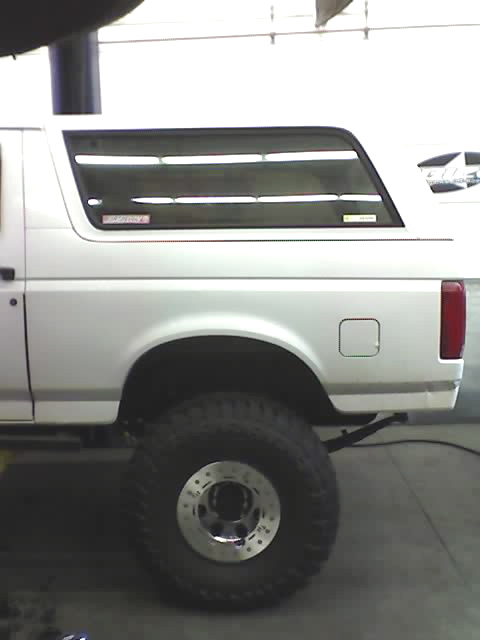1995 Ford Bronco - Side profile of a white 1995 Ford Bronco with large off-road tires.