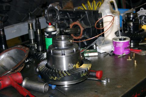 1995 Ford Bronco - Various automotive differential and transmission components are laid out on a workbench, suggesting a repair or rebuild process.