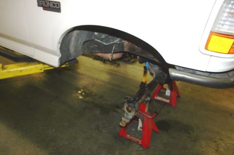 1995 Ford Bronco - Front suspension of a 1995 Ford Bronco undergoing repair, supported by jack stands.