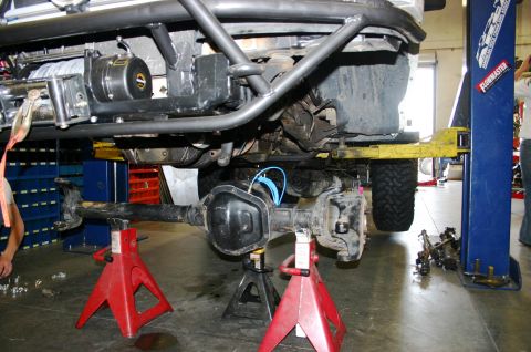 1995 Ford Bronco - The rear axle assembly of an off-road vehicle is detached and supported by red jack stands during maintenance.