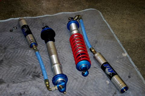 1995 Ford Bronco - Two Fox Racing shock absorbers are laid out on a mat, one a red coil spring.