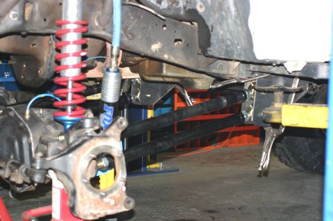1995 Ford Bronco - Close-up of a vehicle's front suspension system, red coilover springs and black control arms.