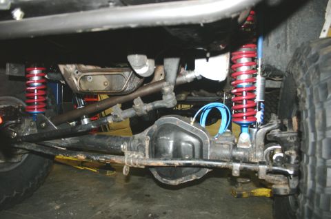 1995 Ford Bronco - Close-up of the undercarriage, highlighting the suspension system with red coilover shocks and the vehicle's differential.