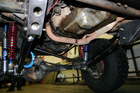 1995 Ford Bronco - The underside of a modified off-road vehicle reveals its suspension and drivetrain components.
