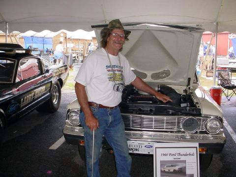 1972 Ford Ranchero - A man stands by a 1964 Ford Thunderbolt, with a black race car visible to the left.
