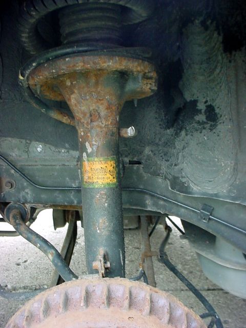 1973 Ford Ranchero - Close-up view of a rusty shock absorber and suspension components, including a brake drum and part of the chassis.