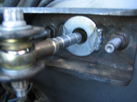 1990 Ford Bronco - Close-up of a vehicle steering or suspension linkage, a tapered shaft passing through a welded steel bracket with a stud nearby.