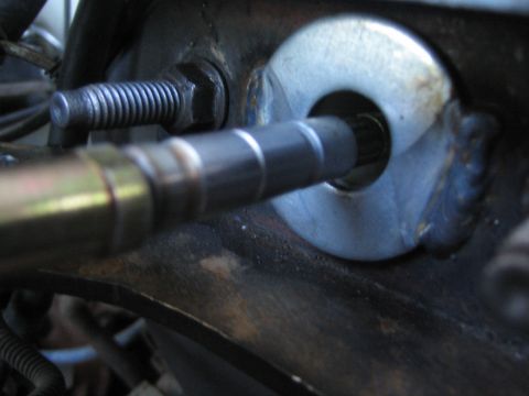 1990 Ford Bronco - Close-up of a tapered steering or suspension shaft passing through a welded bracket, a threaded bolt visible at the left.