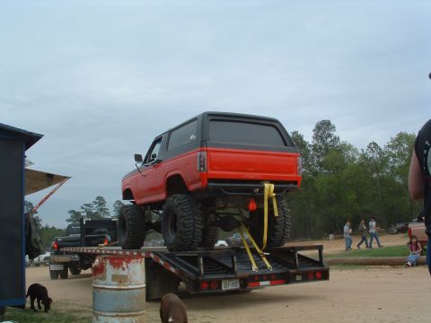 1993 Ford Bronco - A lifted red Bronco is secured to a trailer, ready for transport.