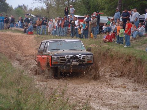 1993 Ford Bronco - A crowd watches as a Ford Bronco navigates a muddy obstacle course.