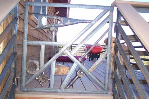 1990 Ford Bronco - A gate made of metal and car parts stands on a deck, with a dog visible behind it.
