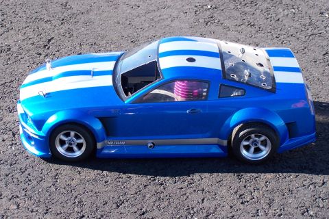1994 Ford Bronco - A blue and white striped remote control car sits on a gravel surface, showing its side profile.