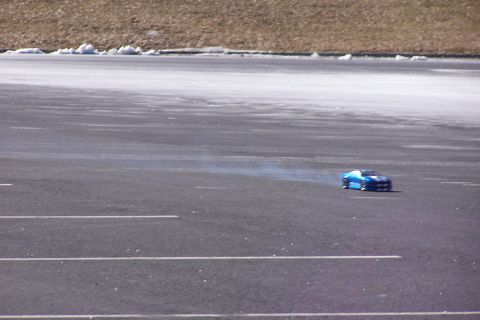 1994 Ford Bronco - A blue remote control car is driving on a paved surface, emitting smoke.