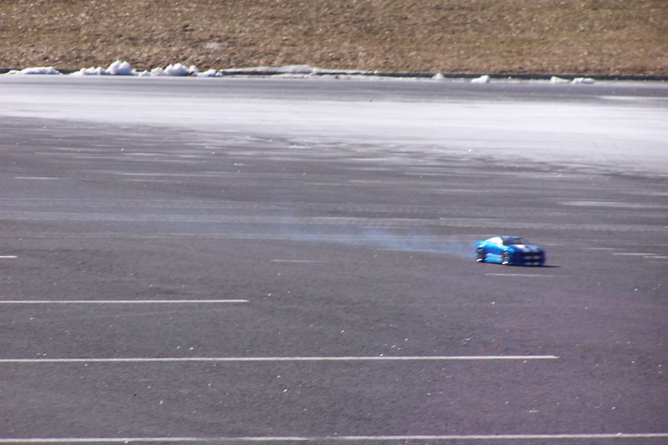 Blue remote control car on asphalt with smoke trailing