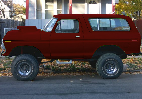 Lifted red SUV with a hood scoop and large tires parked on a street