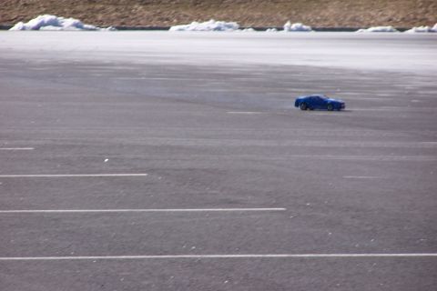 1994 Ford Bronco - A small blue car is seen from the side on a paved surface with white markings.