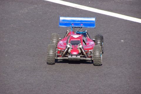 1994 Ford Bronco - A remote control buggy with a blue spoiler sits on a track with a white line.