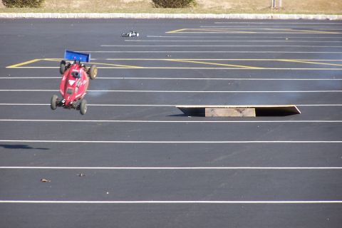 1994 Ford Bronco - A remote control buggy takes flight on a race track, with another vehicle in the distance.