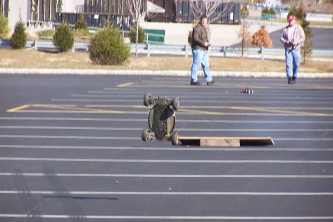 1994 Ford Bronco - Two men operate remote-controlled cars on a paved lot with a wooden ramp.