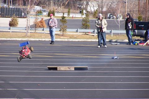 1994 Ford Bronco - Remote control cars race on a track while onlookers supervise.