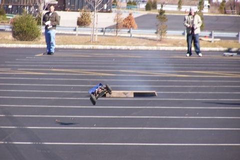 1994 Ford Bronco - A remote control car takes flight over a ramp in a parking lot.