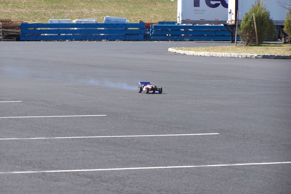 RC buggy driving on asphalt with smoke coming from it