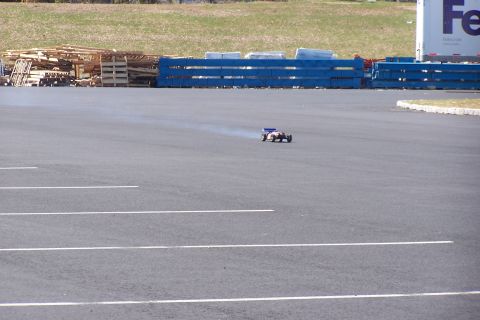 1994 Ford Bronco - A remote-controlled car kicks up dust while driving on a paved surface near a FedEx truck.
